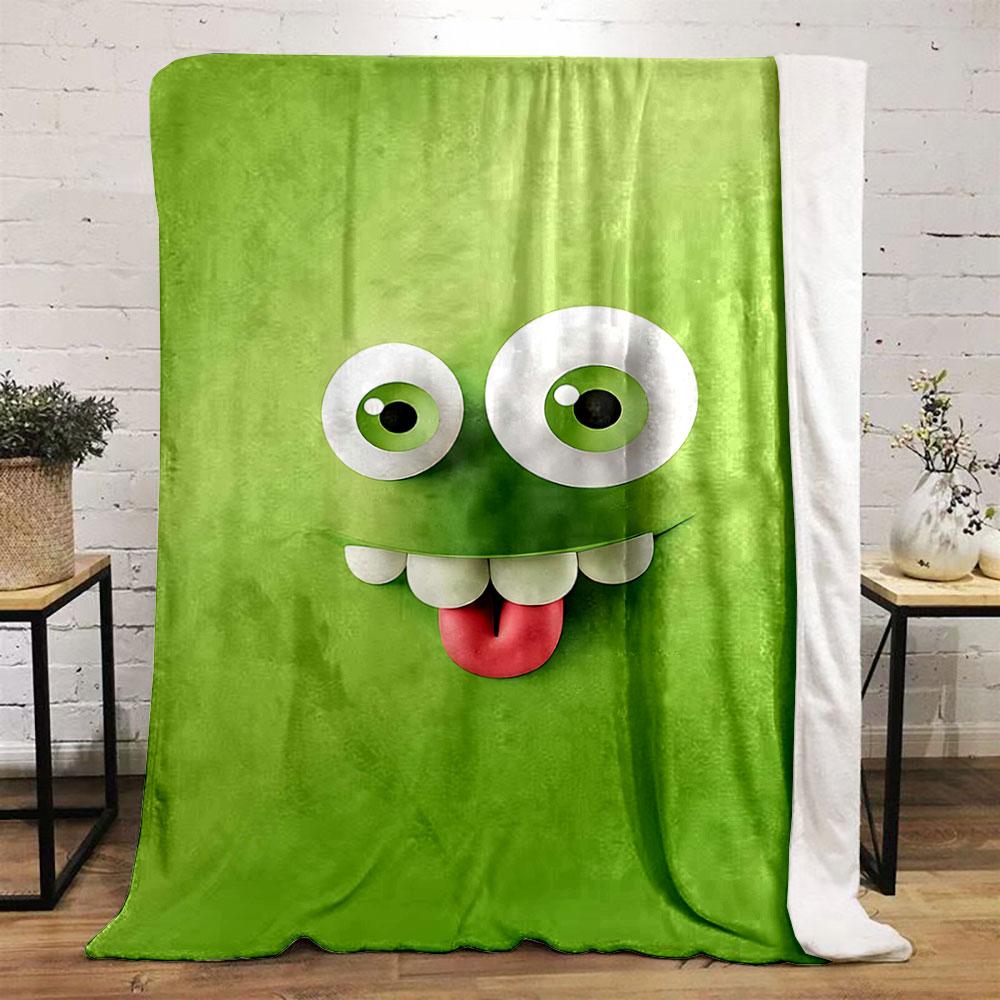 A playful green cartoon face with big eyes, teeth, and a sticking-out tongue. for all seasons blanket lunch break throw gift