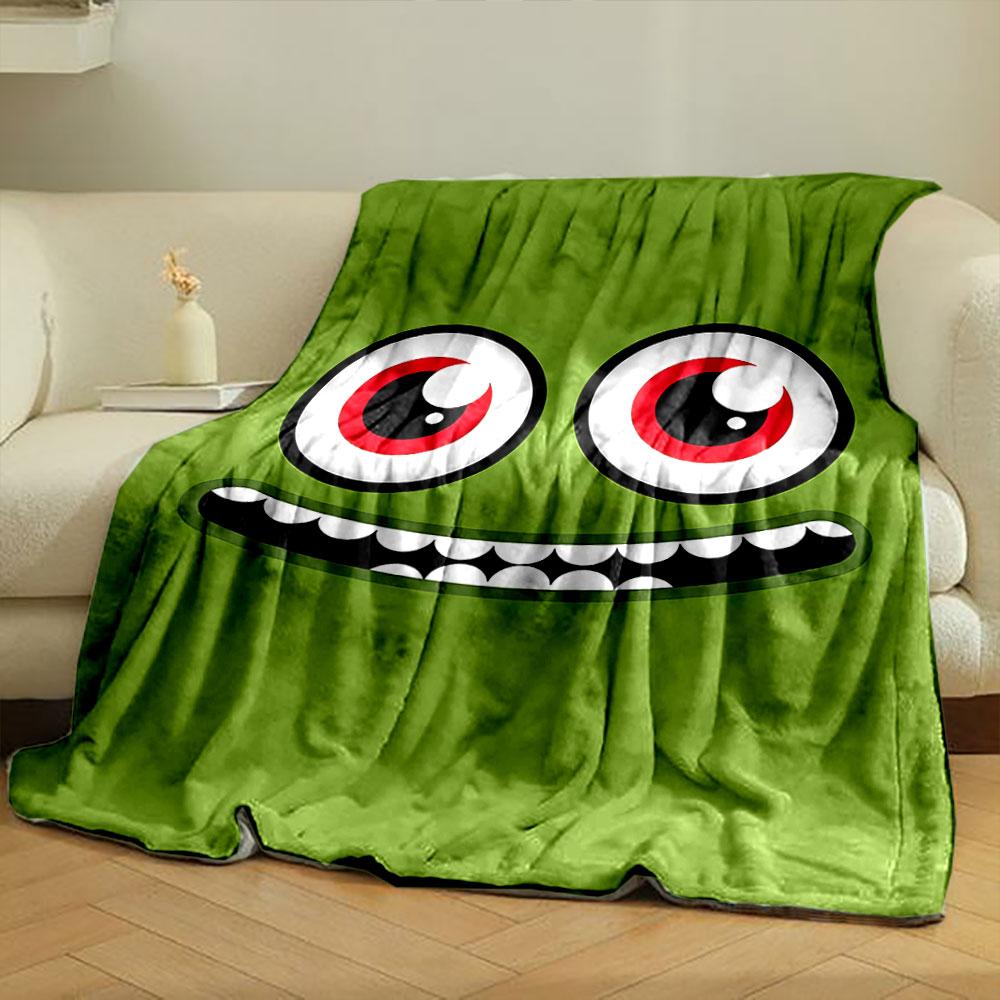 A green face with large red eyes and a wide, toothy grin. for all seasons blanket lunch break throw gift