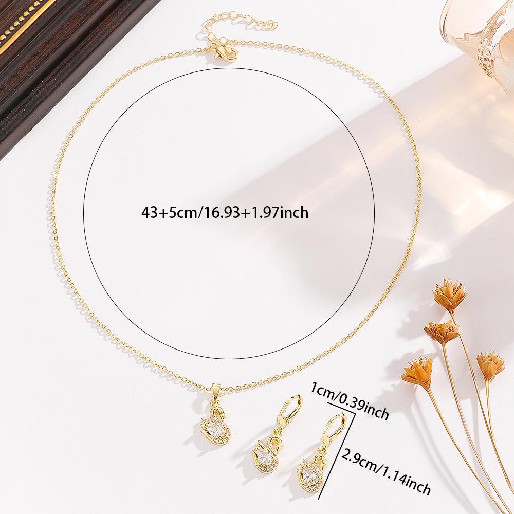 This elegant three-piece set of swan-shaped copper pendant necklace and earrings is a versatile fashion accessory for women, featuring a geometric