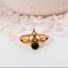 Ornate Black Onyx Crown Ring: Gold-toned Jewelry with a Round Black Cabochon and a Delicate Lotus or Tiara-style Setting.