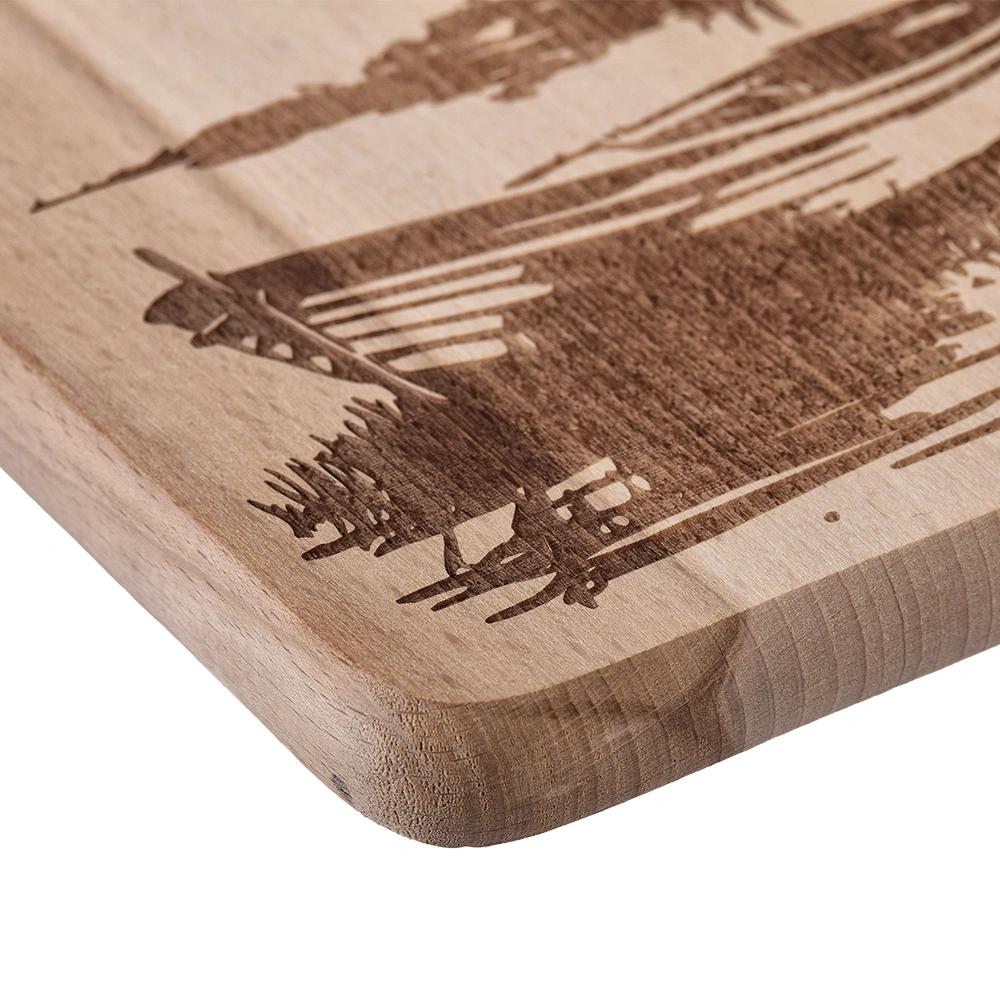 Wooden chopping board engraved with a boat on a lake