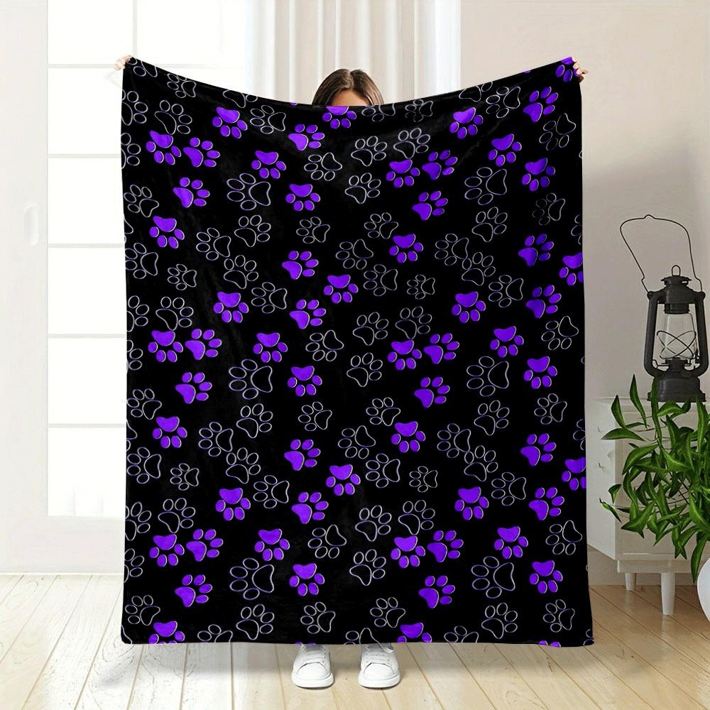 Purple and outlined paw prints scattered on a black background. for all seasons blanket lunch break throw gift