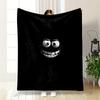 A glowing, cartoonish face with wide eyes and a big toothy grin on black. for all seasons blanket lunch break throw gift