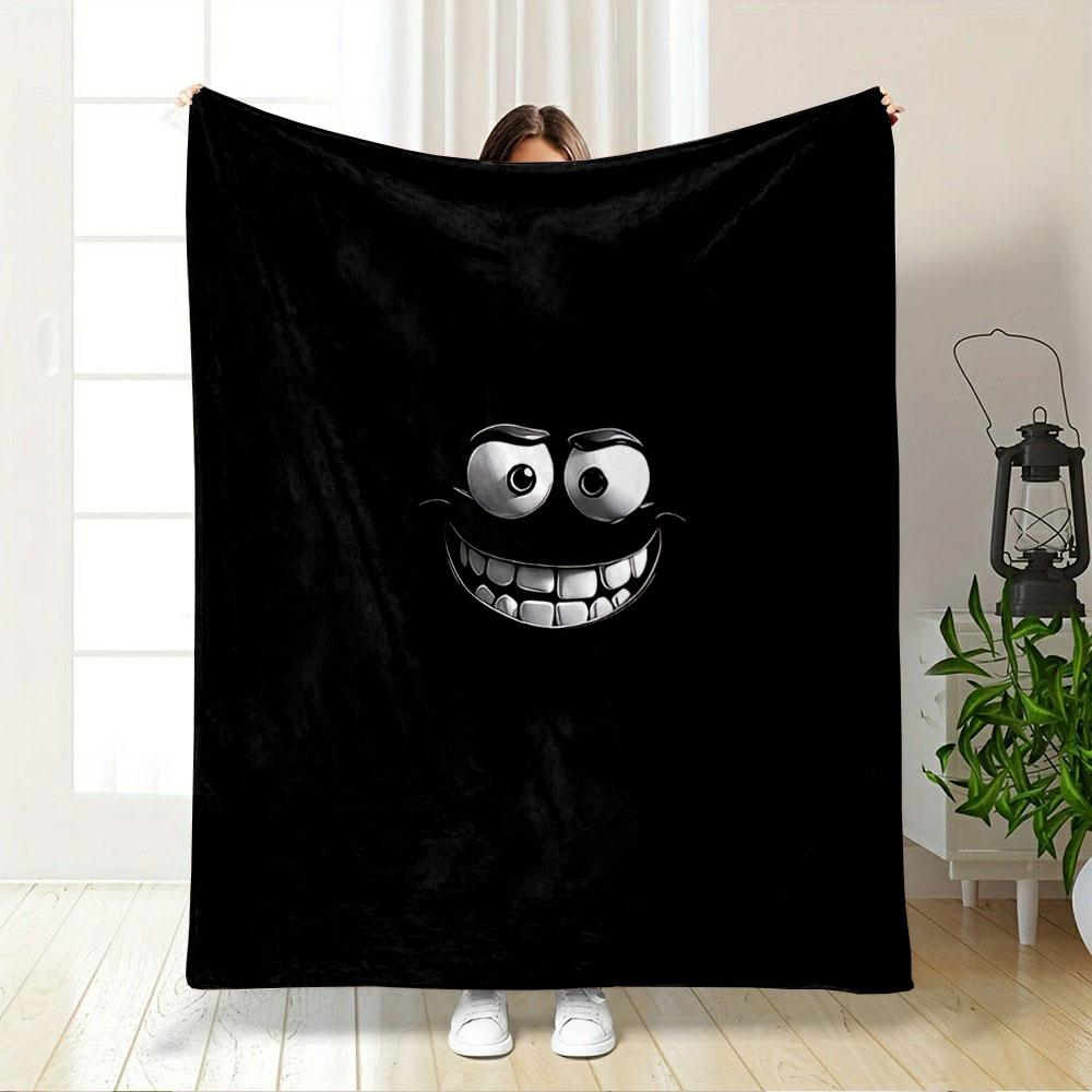 A glowing, cartoonish face with wide eyes and a big toothy grin on black. for all seasons blanket lunch break throw gift
