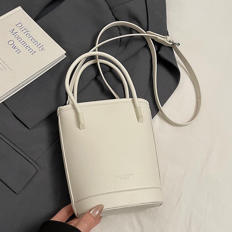 Оптовая продажа новых нишевых простых однотонных сумок-ведер с текстурой «личи», для ношения в руке, универсальных, в зарубежном стиле, для поездок на работу, мессенджеров, женских сумок