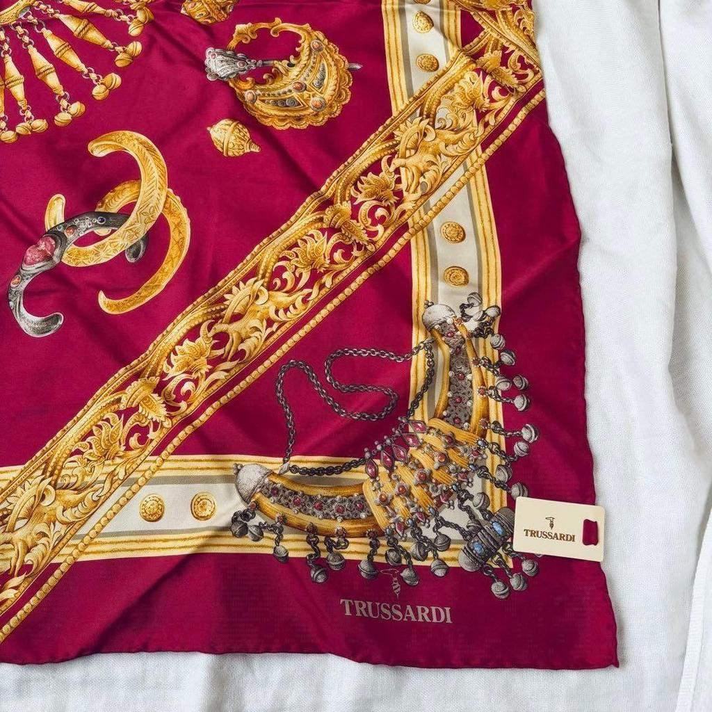 Шелковый платок Trussardi б/у, большого размера, с бирками, золотыми украшениями и ярким узором.
