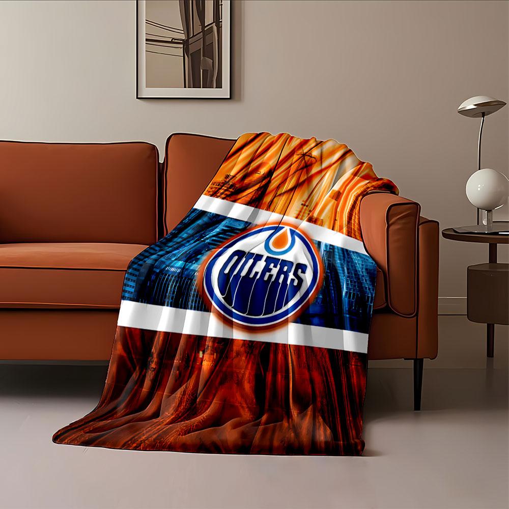 A stylized Oilers logo with orange and blue cityscape and fabric design. for all seasons blanket lunch break throw gift