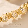 \nBall-shaped lucky charm made of synthetic zirconium plated with gold18K Gold bracelet A versatile gold-plated bracelet with a touch of luxury charm