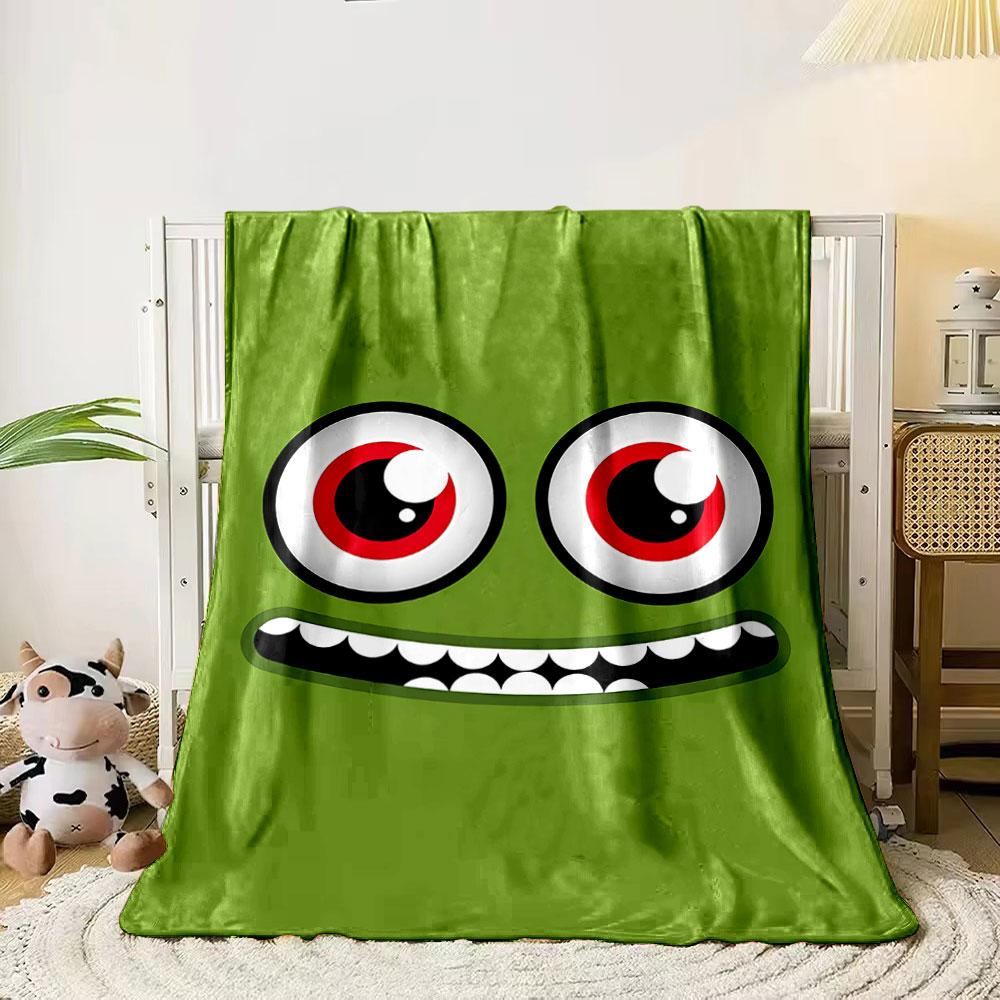 A green face with large red eyes and a wide, toothy grin. for all seasons blanket lunch break throw gift