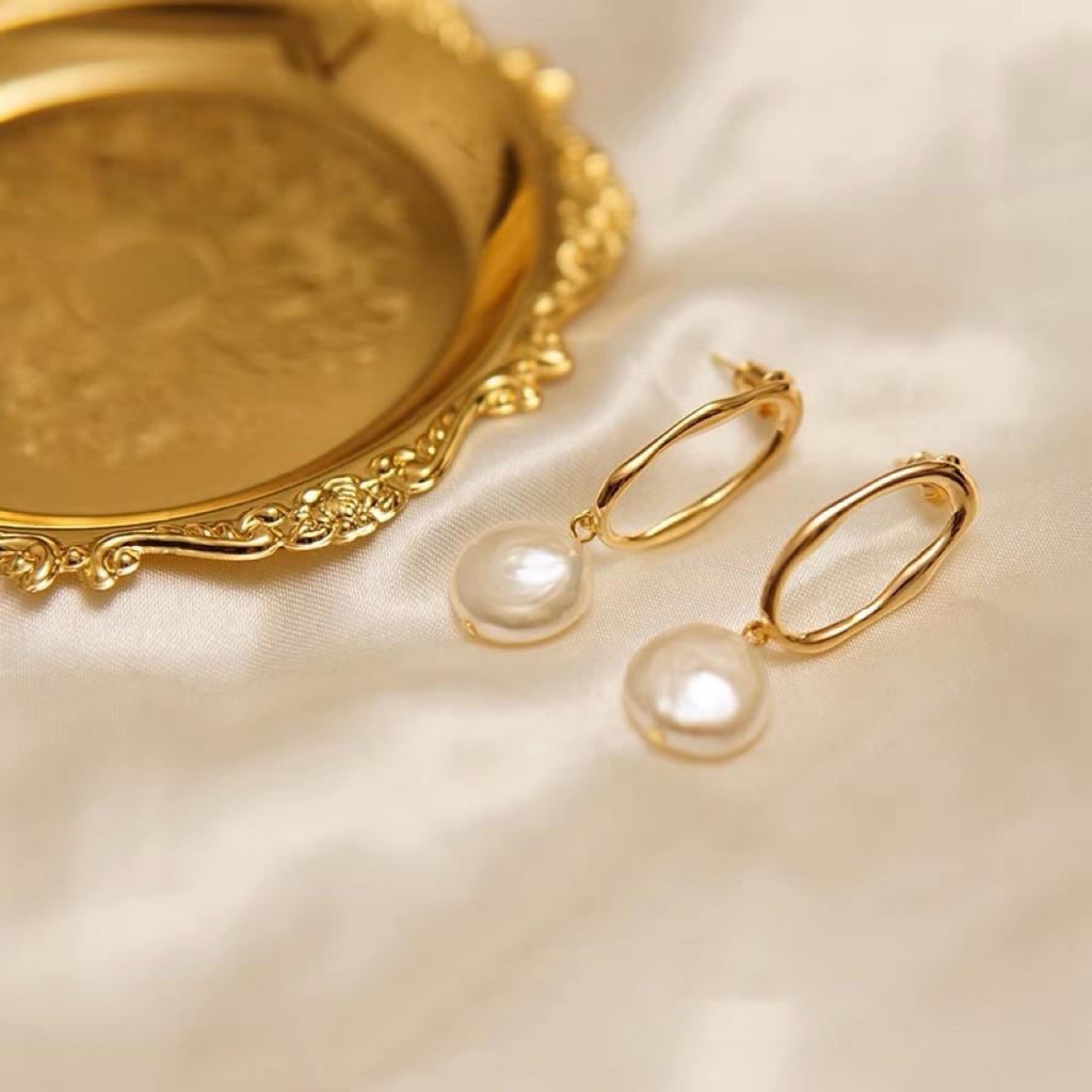 Natural pearl button-style earrings with a strong, hollow geometric oval design, exuding an elegant, minimalist, and versatile chic style