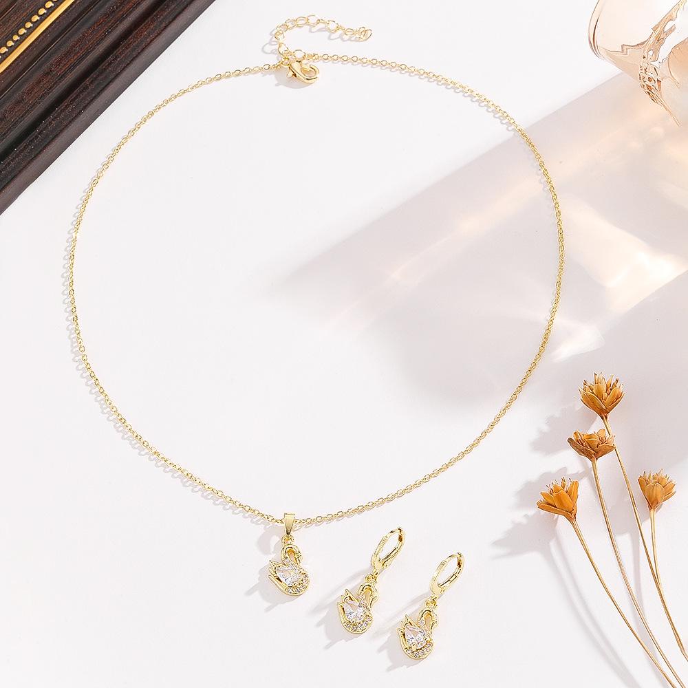 This elegant three-piece set of swan-shaped copper pendant necklace and earrings is a versatile fashion accessory for women, featuring a geometric