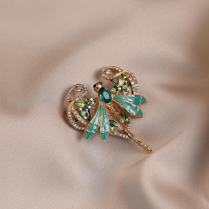 Изысканная зеленая брошь-стрекоза с масляными каплями излучает ощущение роскоши. Это высококлассная изумрудная брошь в виде насекомого.