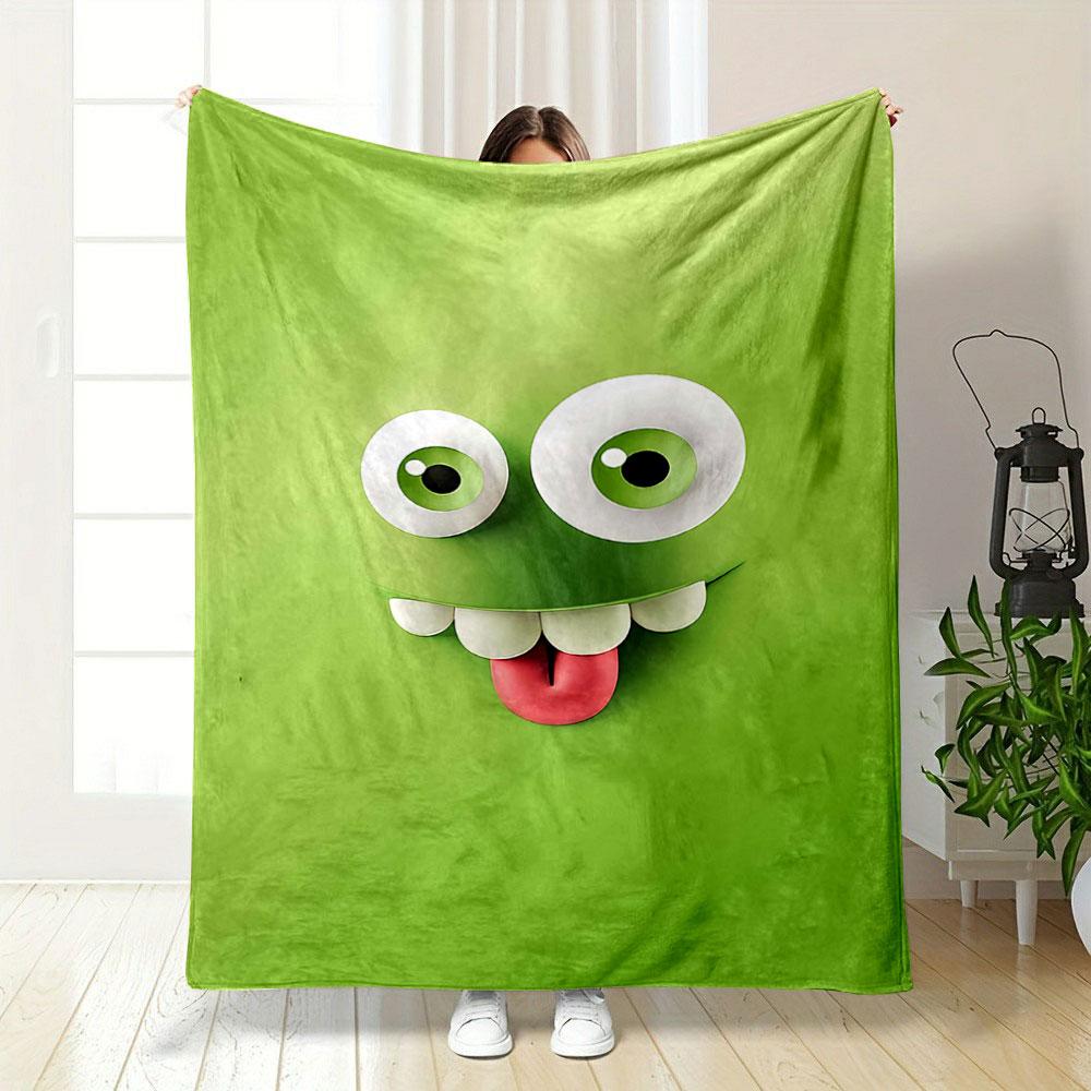 A playful green cartoon face with big eyes, teeth, and a sticking-out tongue. for all seasons blanket lunch break throw gift
