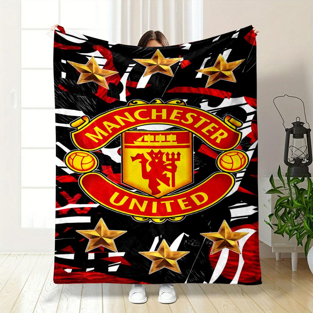 A Manchester United logo surrounded by gold stars on a red-black pattern. for all seasons blanket lunch break throw gift