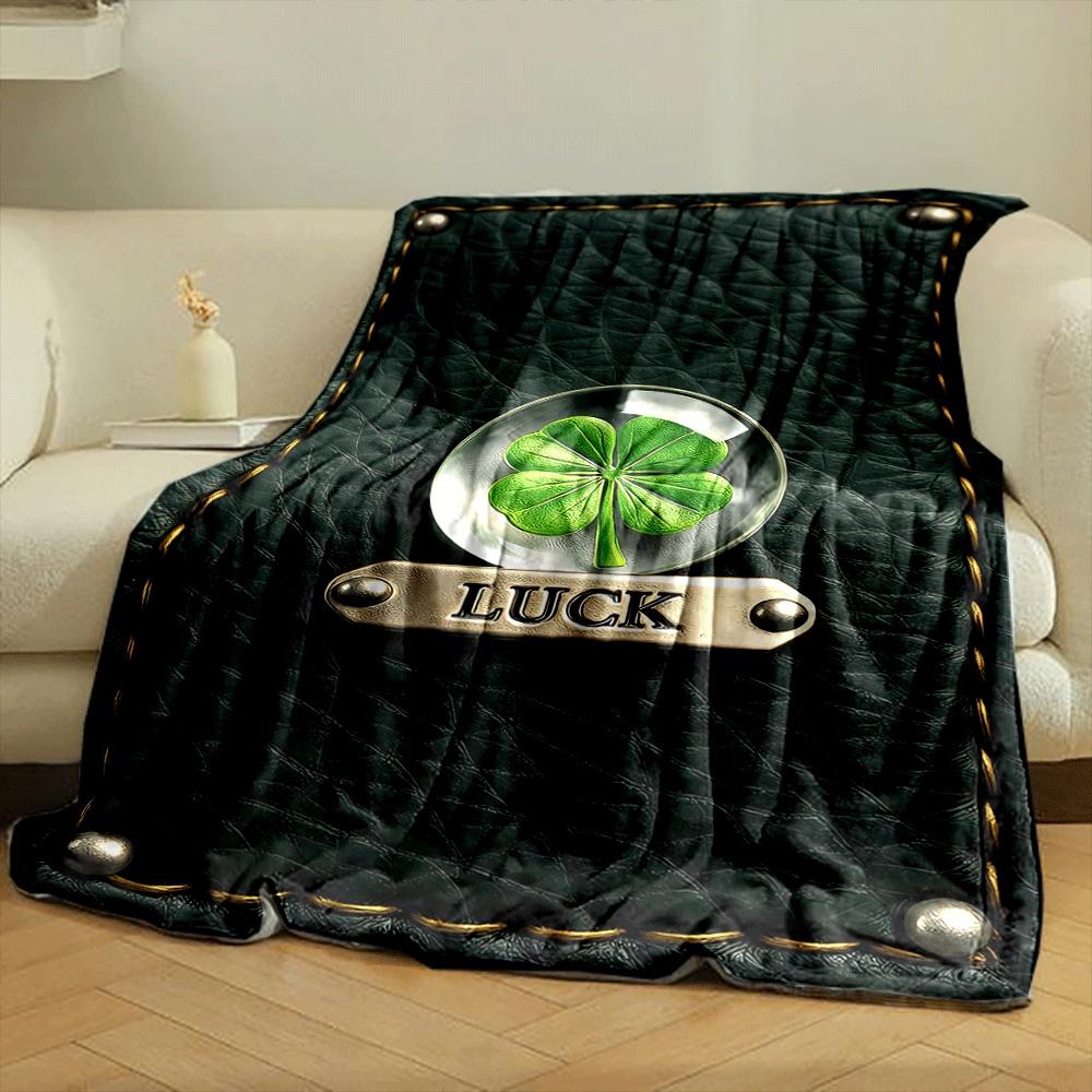 A four-leaf clover encased in glass, labeled "LUCK" on stitched leather. for all seasons blanket lunch break throw gift
