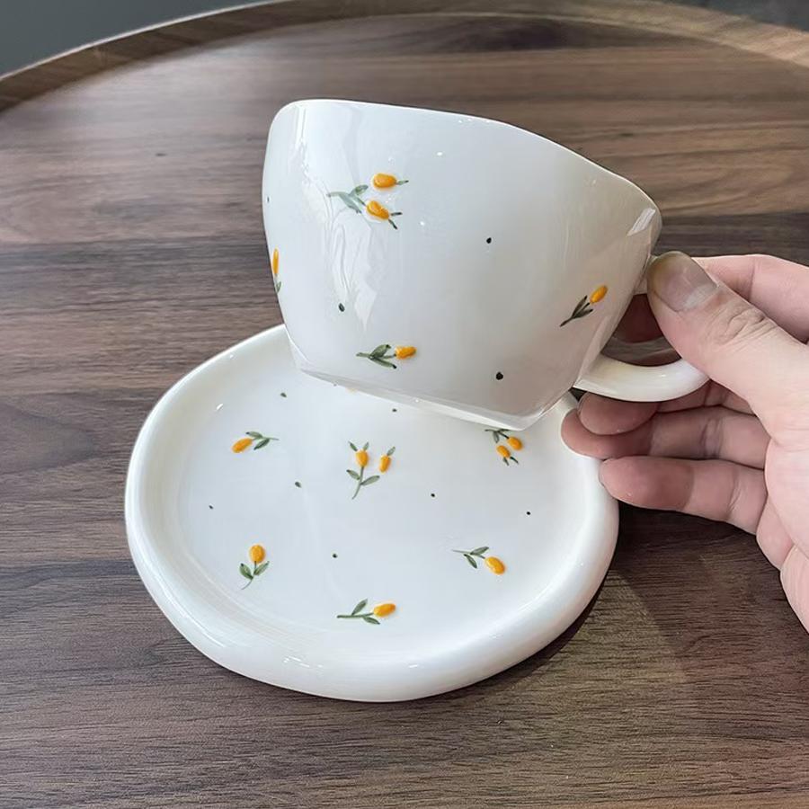 Керамический кофейный набор (чашка и блюдце), украшенный мелким цветочным узором.