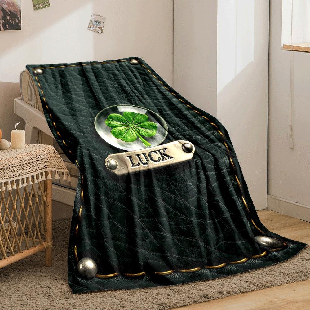 A four-leaf clover encased in glass, labeled "LUCK" on stitched leather. for all seasons blanket lunch break throw gift